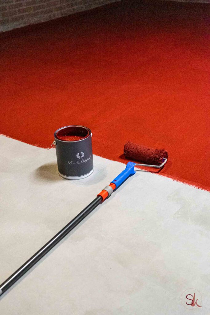 Betonvloer schilderen met rode vloerverf uit blik met een roller