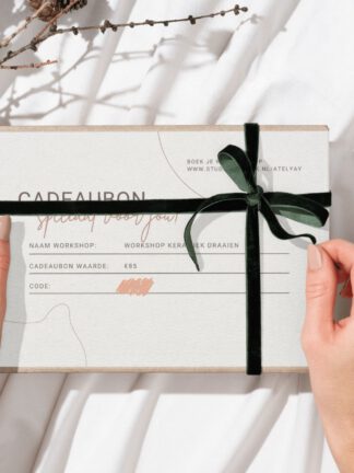 Mockup cadeaubon workshop keramiek kleien draaien draailes handvormen cursus AtelYAY Iris Floor Ceramics STUDIO kapstok gift voucher workshop handen houden cadeau vast