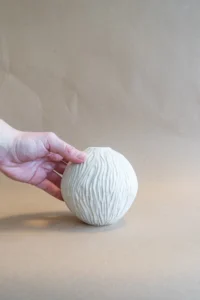 Mini moonjar vaas van voren, wordt vastgehouden door een hand, met gedetailleerde carvings.